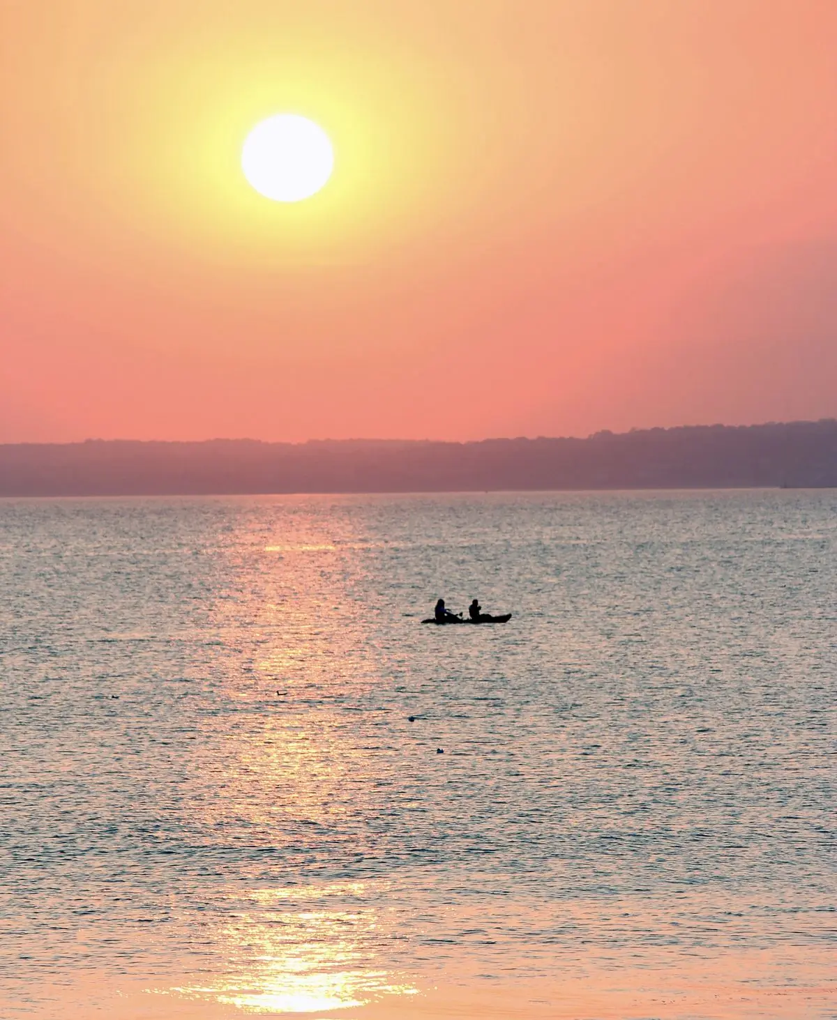 Two kayakers silhouetted on a gold sea at sunset off Aberafan beach