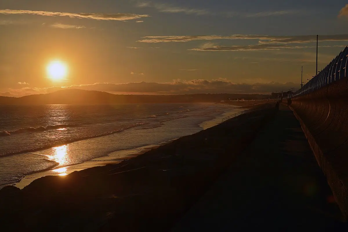 The sun setting over Swansea Bay, seen along the sea wall at Aberavon Sands, Port Talbot